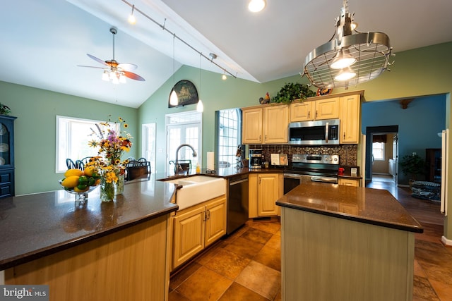 kitchen featuring backsplash, appliances with stainless steel finishes, dark tile patterned flooring, track lighting, and a kitchen island