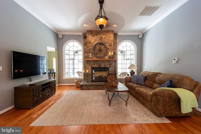 living room with light hardwood / wood-style floors, a stone fireplace, and crown molding