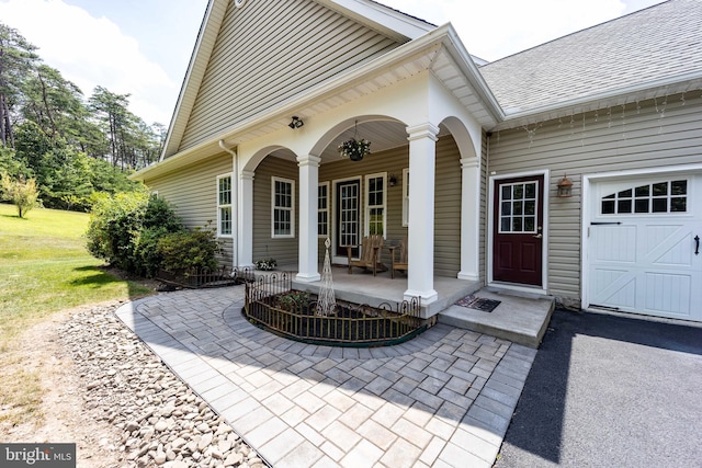 view of exterior entry featuring a garage and covered porch