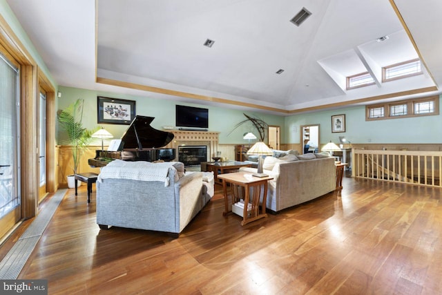 living room featuring vaulted ceiling with skylight and wood-type flooring