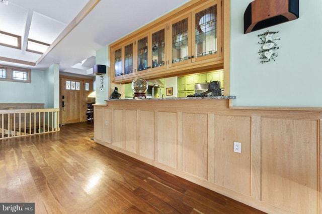 bar with stone counters, light brown cabinets, and hardwood / wood-style floors