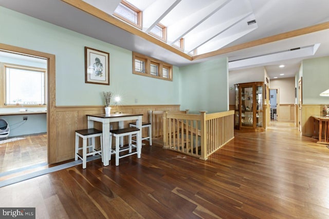 interior space with kitchen peninsula, vaulted ceiling with skylight, hardwood / wood-style flooring, and a kitchen breakfast bar