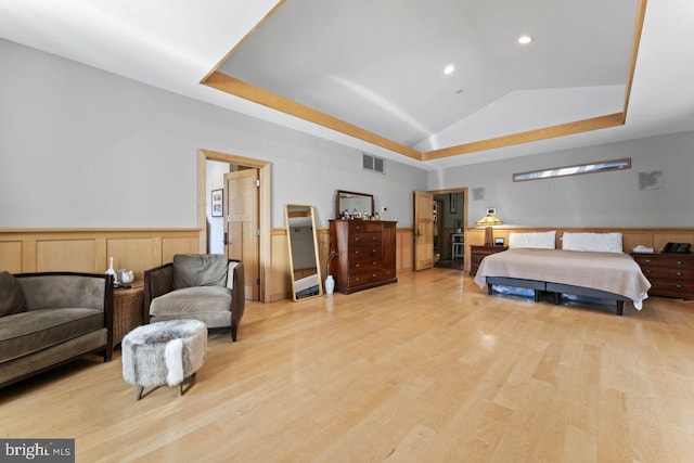 bedroom with light hardwood / wood-style floors and a tray ceiling