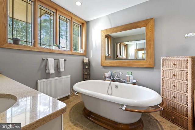 bathroom with vanity, tile patterned flooring, a bathtub, and radiator