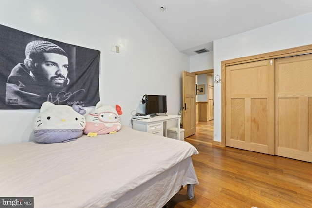 bedroom featuring high vaulted ceiling, a closet, and hardwood / wood-style floors