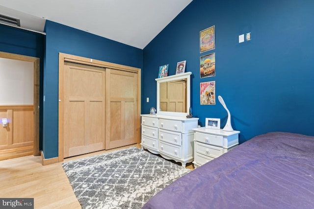 bedroom with hardwood / wood-style flooring, a closet, and high vaulted ceiling