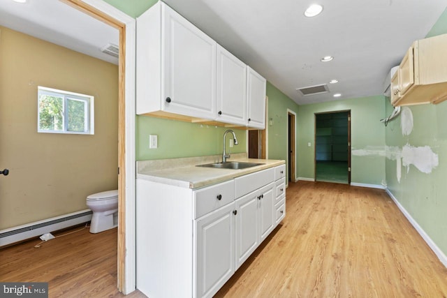 kitchen featuring sink, a baseboard heating unit, light hardwood / wood-style flooring, and white cabinetry