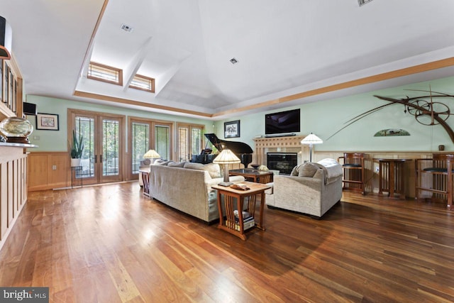 living room with a skylight, wood-type flooring, and a tray ceiling