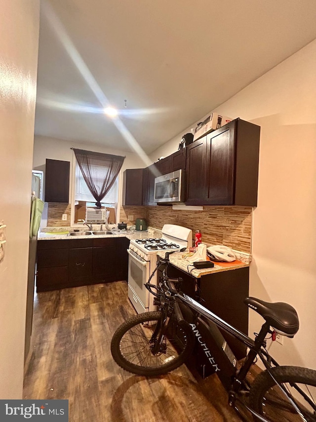 kitchen featuring sink, white range with gas stovetop, dark brown cabinets, dark hardwood / wood-style floors, and decorative backsplash