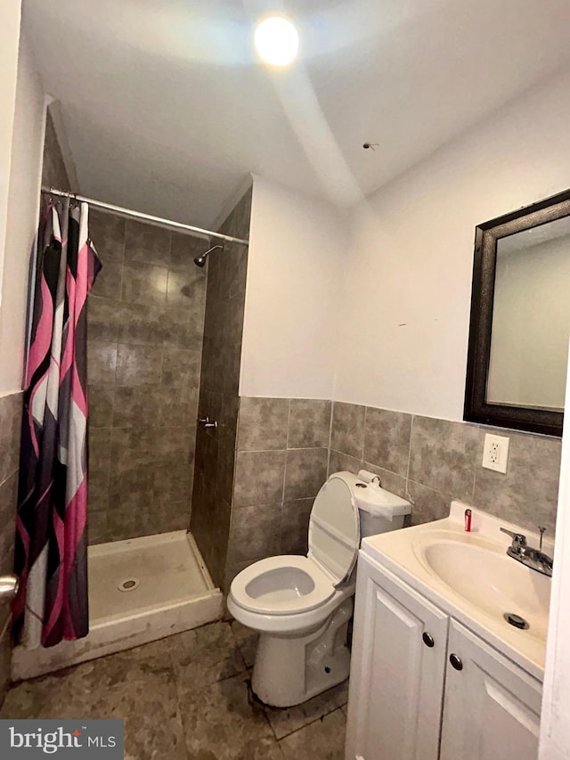 bathroom with vanity, toilet, a shower with shower curtain, and tile walls