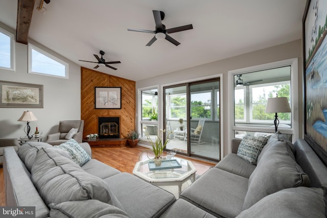 living room with wood walls, light hardwood / wood-style flooring, lofted ceiling with beams, and plenty of natural light