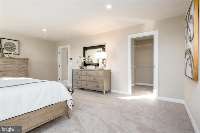 bedroom with a spacious closet, light colored carpet, and a closet