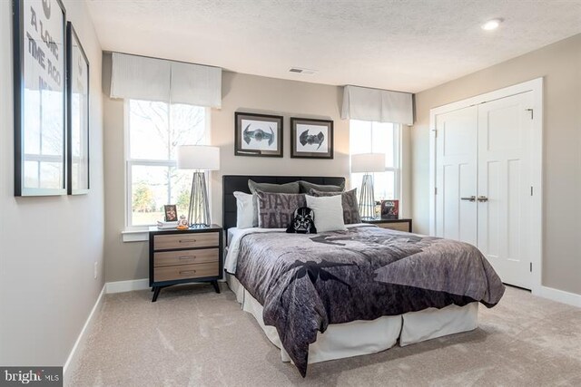 carpeted bedroom featuring a textured ceiling and a closet