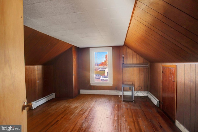 bonus room with dark hardwood / wood-style flooring, a baseboard heating unit, vaulted ceiling, and wooden walls