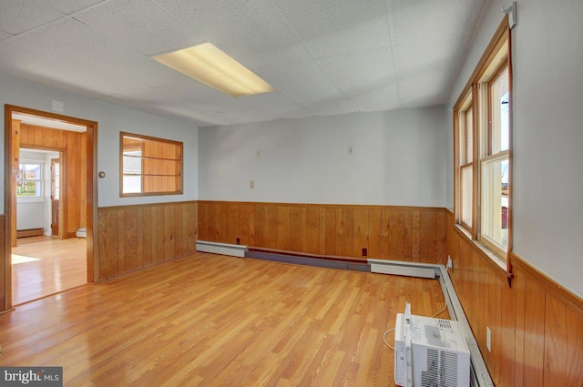 empty room featuring a baseboard heating unit and light hardwood / wood-style floors