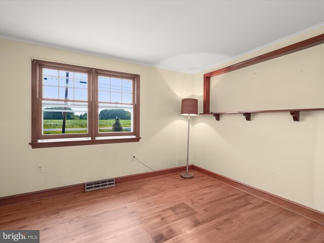 empty room with ornamental molding and light hardwood / wood-style floors