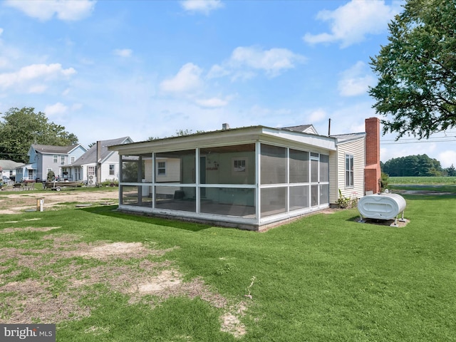 rear view of property featuring a lawn and a sunroom