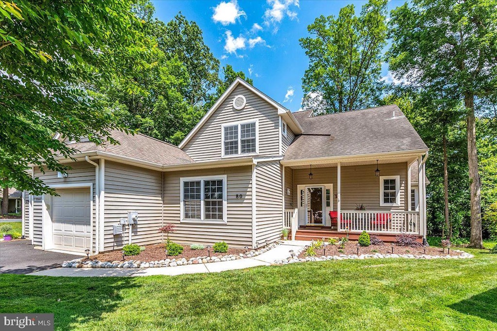 view of front property with a garage, covered porch, and a front lawn