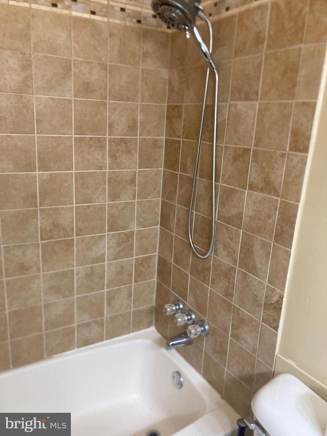 bathroom featuring tiled shower / bath combo and toilet