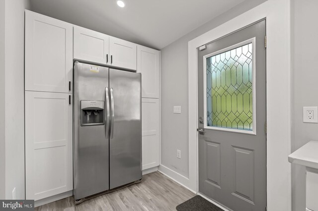 kitchen featuring light hardwood / wood-style floors, stainless steel fridge with ice dispenser, and white cabinets