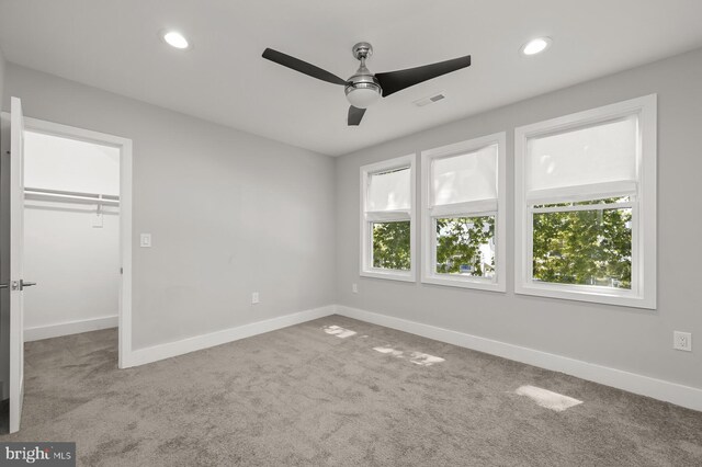 unfurnished bedroom with ceiling fan, light carpet, a closet, and a walk in closet