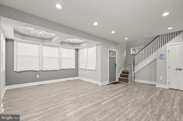 entrance foyer with a raised ceiling and light wood-type flooring