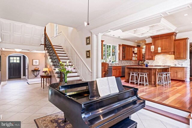 tiled living room featuring ornamental molding and decorative columns