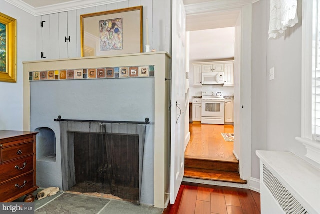 interior space featuring white appliances, wood-type flooring, radiator, and crown molding