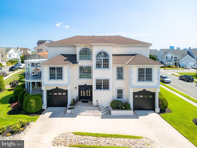 view of front of property featuring a garage, a front yard, french doors, and a balcony