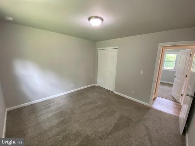 unfurnished bedroom with a closet and dark colored carpet