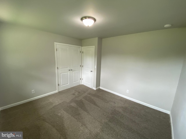 unfurnished bedroom featuring dark carpet and a closet