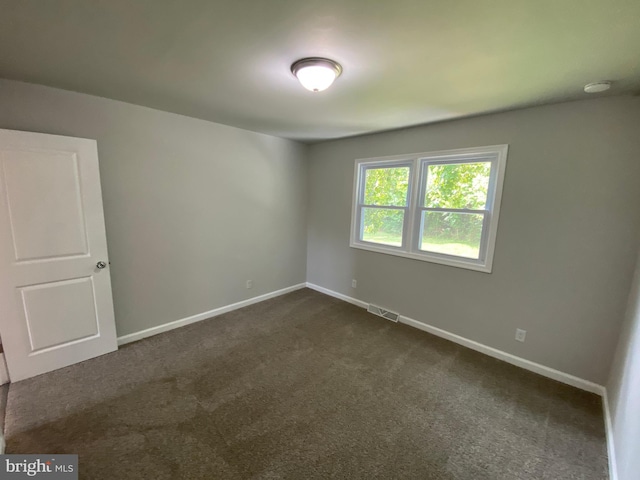 spare room featuring dark carpet