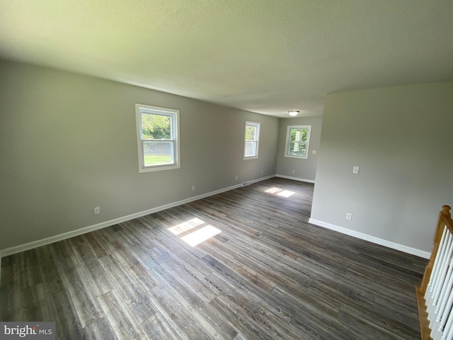 unfurnished room featuring dark wood-type flooring and a textured ceiling