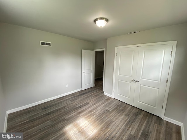 unfurnished bedroom with dark wood-type flooring and a closet