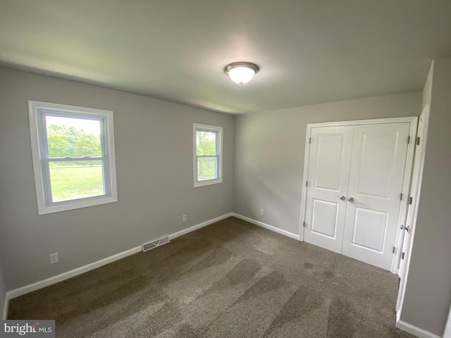 unfurnished bedroom featuring a closet and dark colored carpet