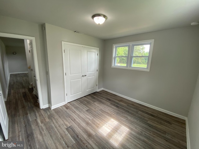 unfurnished bedroom featuring dark wood-type flooring and a closet