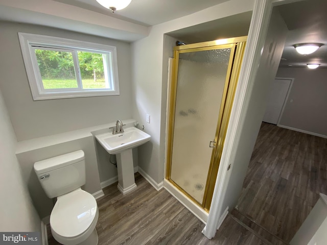 bathroom with toilet, hardwood / wood-style floors, and a shower with shower door