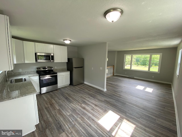 kitchen with dark wood-type flooring, sink, stainless steel appliances, light stone countertops, and white cabinets