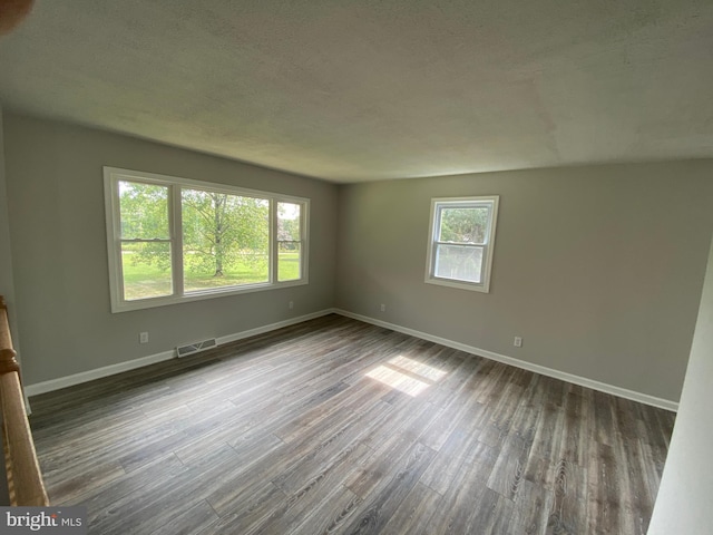 unfurnished room with dark wood-type flooring and a textured ceiling