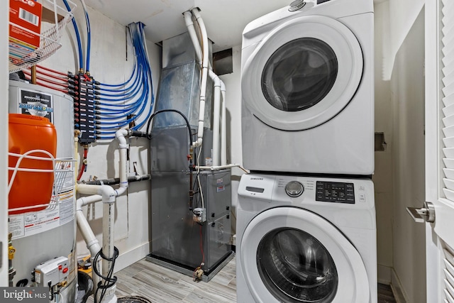 laundry area featuring stacked washer / dryer, light wood-type flooring, and gas water heater