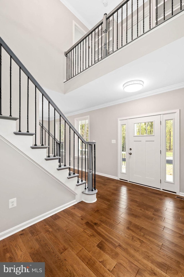 foyer entrance featuring wood-type flooring, a high ceiling, and ornamental molding