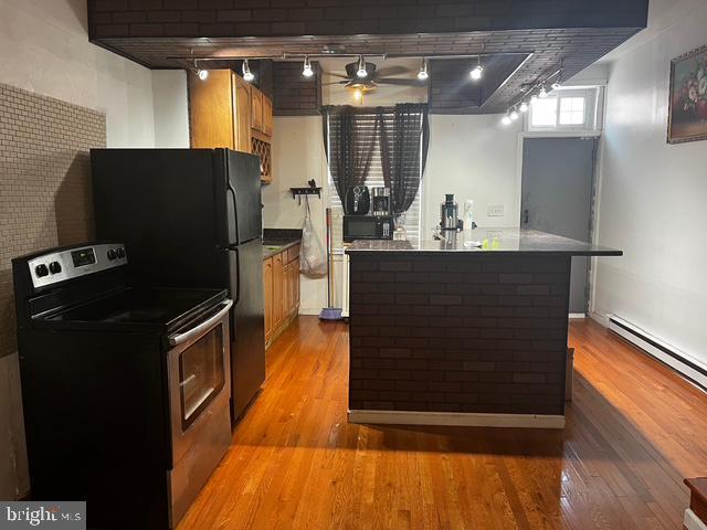 kitchen featuring rail lighting, stainless steel electric range, light hardwood / wood-style flooring, ceiling fan, and a baseboard heating unit