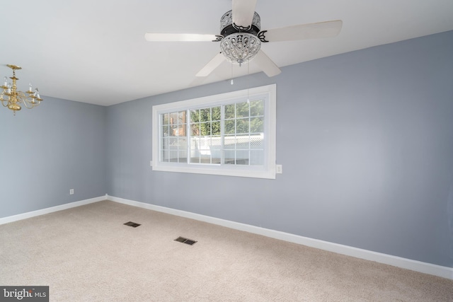 unfurnished room featuring ceiling fan with notable chandelier and carpet floors