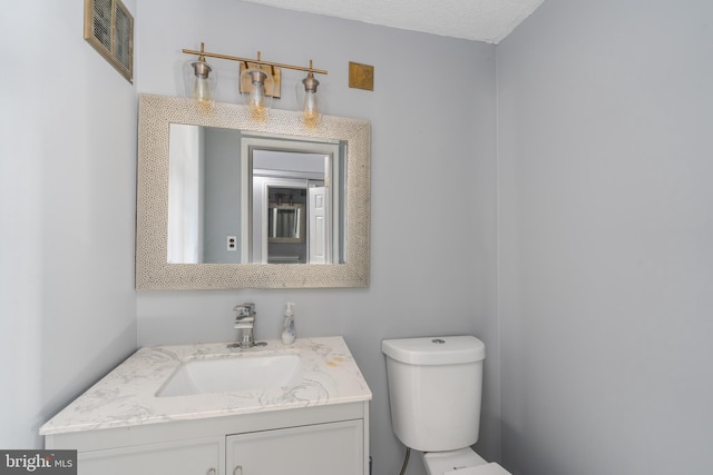 bathroom featuring vanity, toilet, and a textured ceiling