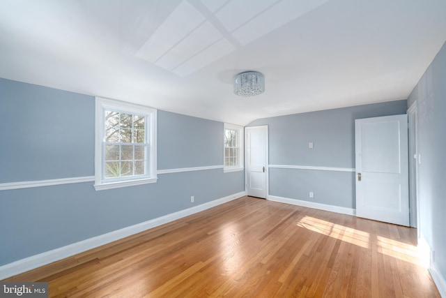 unfurnished room with hardwood / wood-style flooring and vaulted ceiling