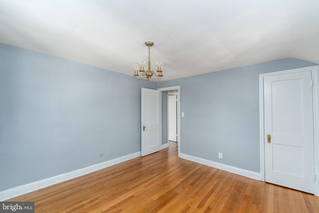 spare room with an inviting chandelier and light hardwood / wood-style flooring