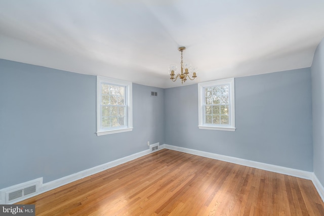 spare room featuring hardwood / wood-style flooring and a notable chandelier