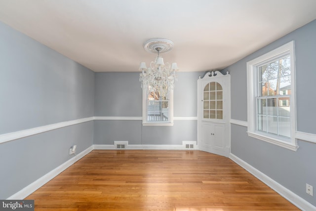 unfurnished dining area featuring an inviting chandelier and light wood-type flooring