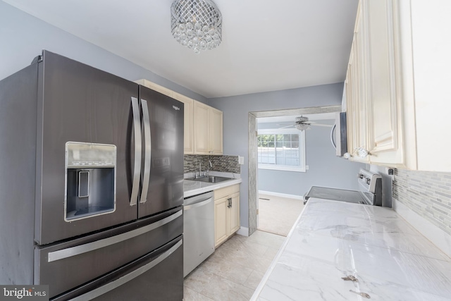 kitchen with appliances with stainless steel finishes, tasteful backsplash, sink, light tile patterned floors, and ceiling fan