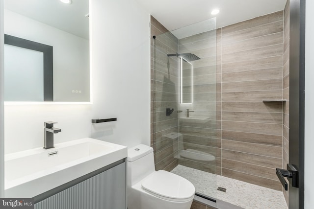 bathroom with vanity, toilet, and a shower with door